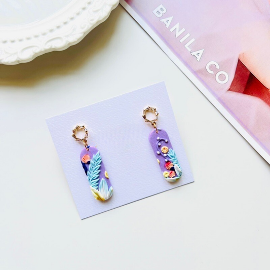 Colorful clay earrings on a card with 'Banila Co' branding in the background